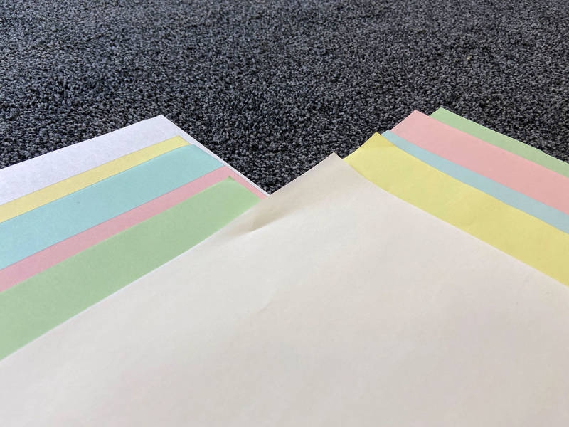 Papierbögen in den Farben weiß, gelb, hellblau, rosa und hellgrün.